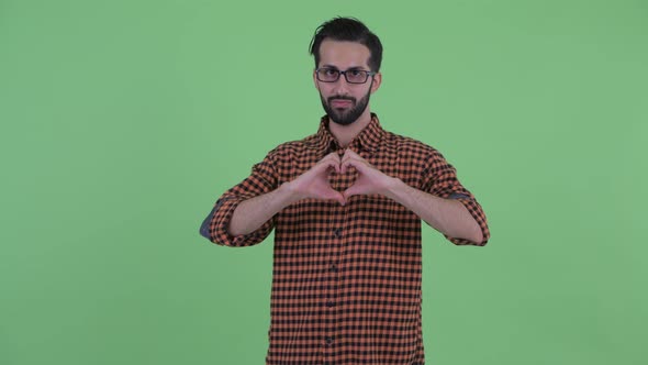 Happy Young Bearded Persian Hipster Man with Hand Heart Gesture