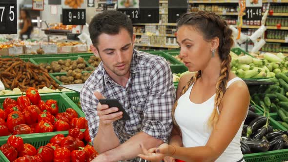 Couple Checking List on Their Smart Phone While Shopping for Food