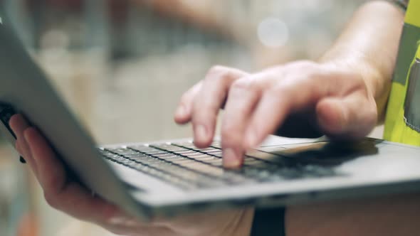 Close Up of Laptop Keyboard with a Male Employee Typing on It