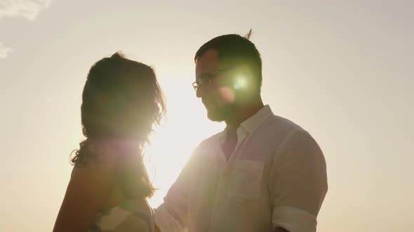 Silhouettes of Man and Woman Kissing Against the Sky in a Hot Sunny Day