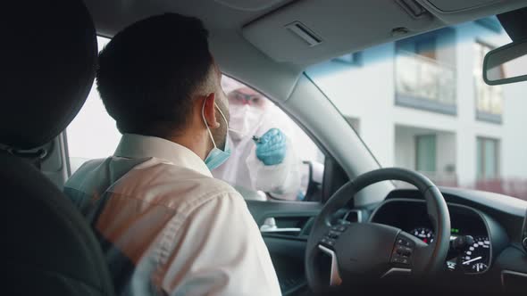 Nurse Performing Swab Test on the Man in the Drivers Seat