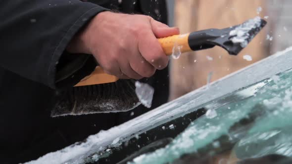 Person in Black Jacket Hands Clean Snow From Windshield