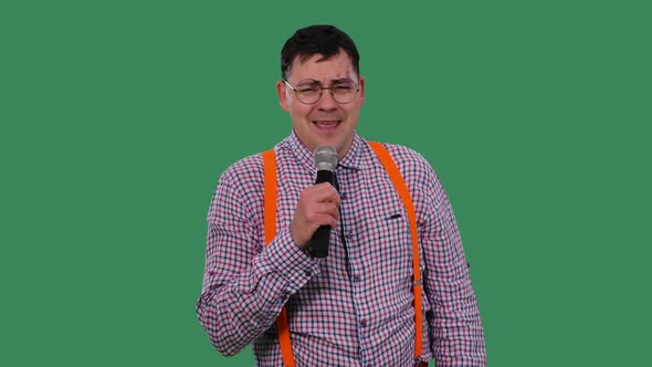 Portrait of a Man Singing with a Microphone in His Hand on a Green Screen