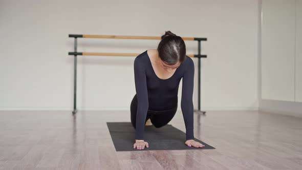 a Beautiful Dancer in Black Clothes Lies on a Mat in a Dance Class and Stretches Her Legs and Back