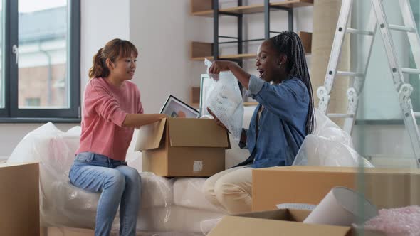 Women Moving to New Home and Unpacking Boxes