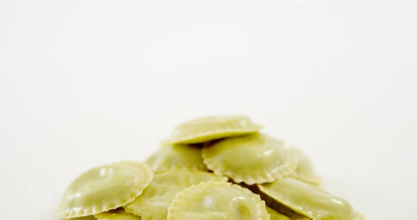 Stack of green homemade ravioli pasta on white background