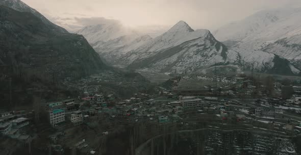 Wide rotating shot of houses build up above the mountain with snow caped mountain in the background.