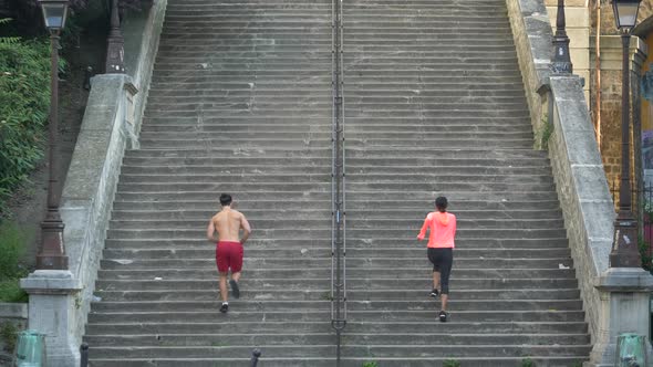 A couple running on stairs in a city as a workout