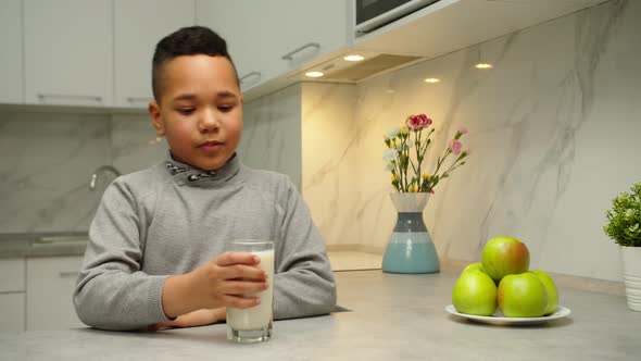 Lovely Black Boy Drinking Milk Looking at Camera Indoors