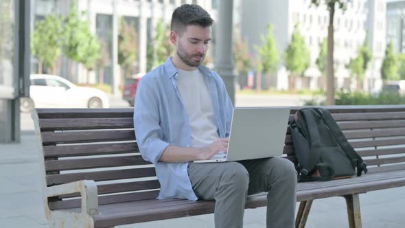 Young Man Using Laptop While Sitting on Bench