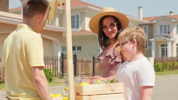 Boy Buying Lemonade Outdoors In Summer