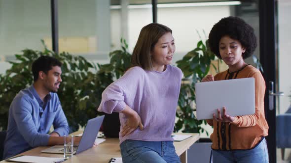 Diverse business people talking using a laptop in modern office