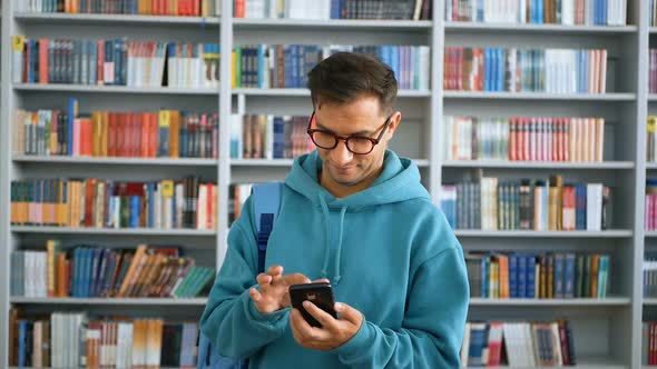 Closeup Portrait of a Young Attractive Student Guy He is Texting with Friends on His Smartphone