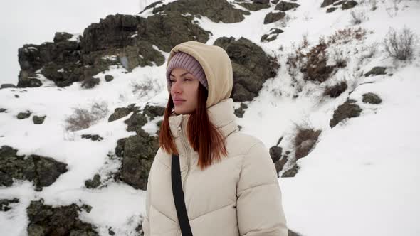 Attractive Young Girl Tourist Stands in the Woods in the Mountains in Winter