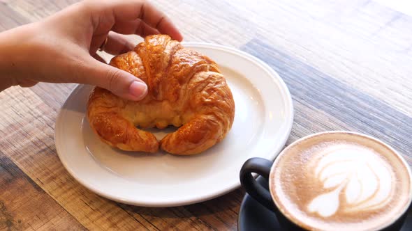  Women Hand Holding a Croissant and Late Coffee on Table 