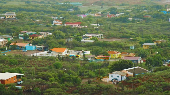Colorful school buses traveling on the road of Curacao - Aerial shot