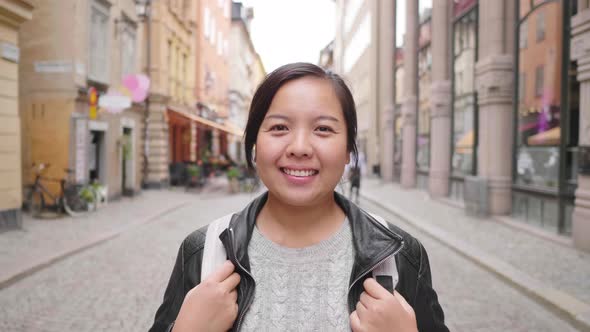 Front view of Asian woman standing and smiling on street in Sweden