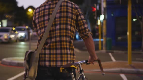 Caucasian male riding his bike and crossing the road in a street in the evening