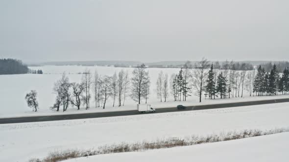 Delivery Van Driving on Winter Country Road, Aerial View From Drone in . Tracking Shot