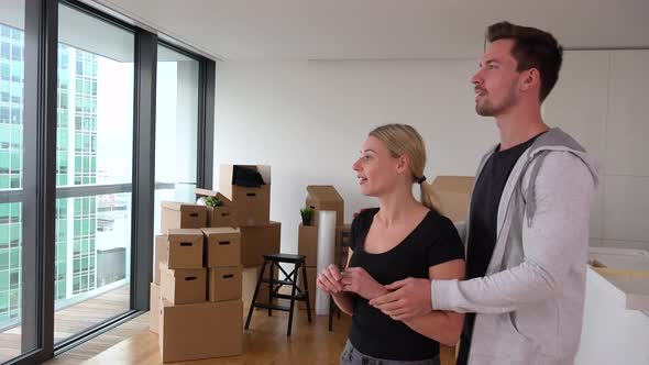 A Happy Moving Couple Talks About Their New Apartment, Then Looks Out a Window - Cardboard Boxes