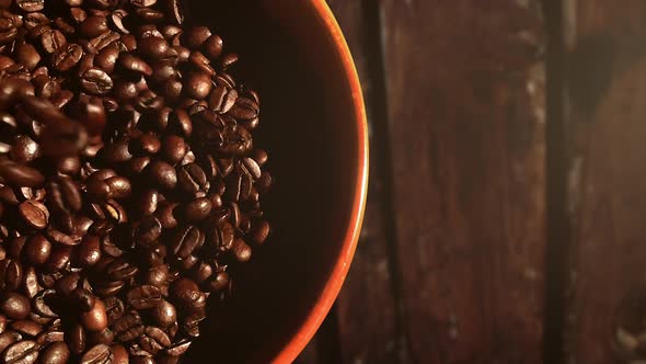Dropping coffee beans into a bowl. No camera movement. Steady slow motion shot.