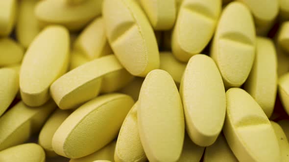 Bright Yellow Antibiotics and Antiviral Pills Lie Together and Rotate Closeup