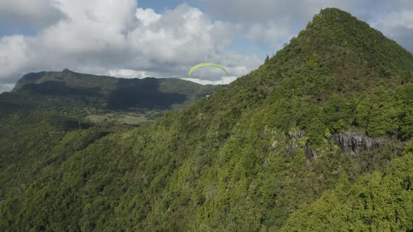 Aerial view of a person doing paragliding among the mountain, Mauritius.