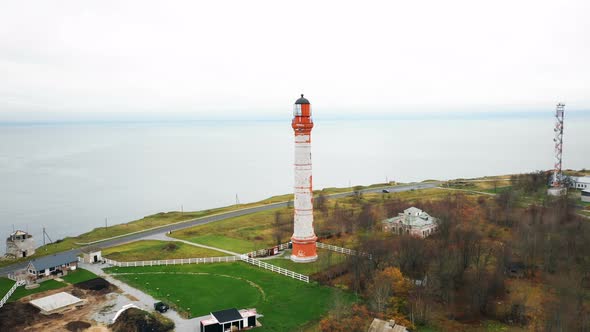 Incredible Aerial Panning Shot of Beautiful Old Lighthouse and Buildings Around on Picturesque Sea