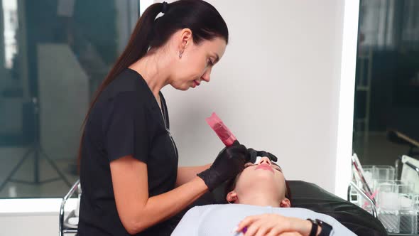 Master Makes Permanent Eyebrow Makeup Procedure to Woman in Beauty Salon