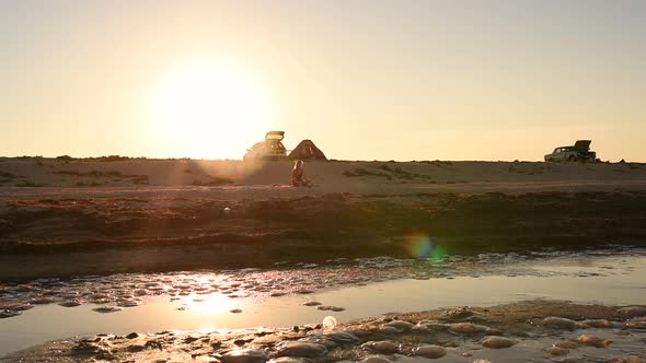 Woman in Bikini Swimsuit with Long Hair Runs Along the Seashore Against Setting Sun