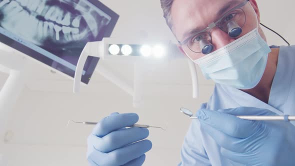 Caucasian male dentist with face mask examining teeth at modern dental clinic