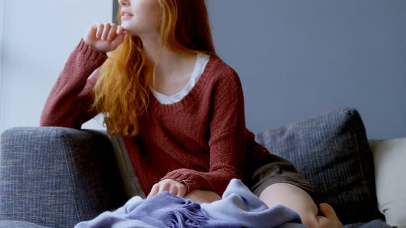 Woman looking through window in living room at home