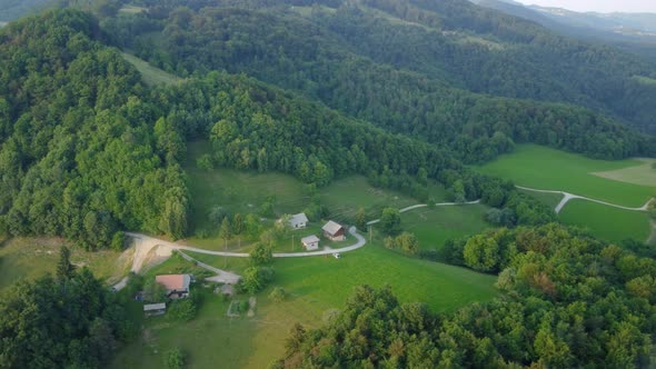 Green hills covered with trees and meadows with some remote family farms. Aerial 4k view.