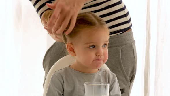 Crop Mother Doing Hair of Daughter in Morning