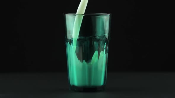 Milk Pouring Into Faceted Green Glass Close Up Isolated on Black Background Slow Motion