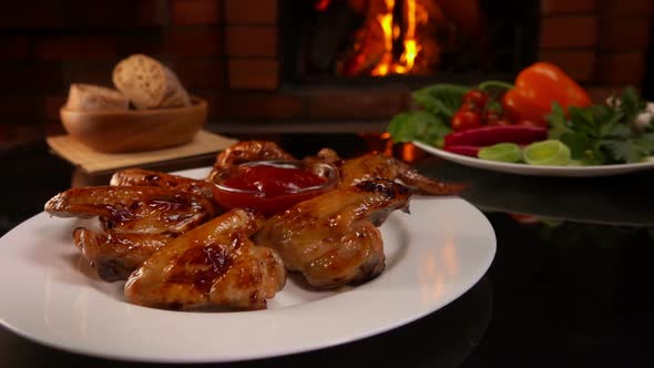 Panorama of Plate Full of Grilled Chicken Wings on a Background of a Fireplace