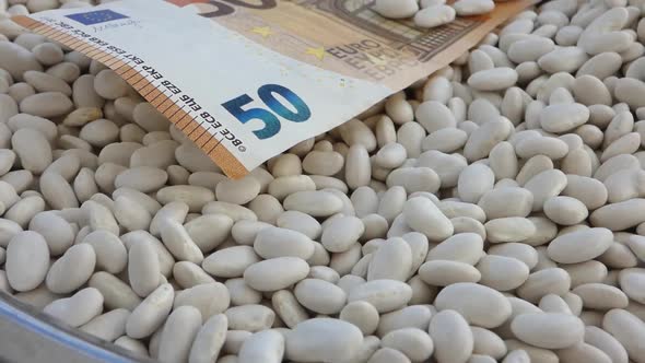 a bowl of white beans and a 50 euro paper note,