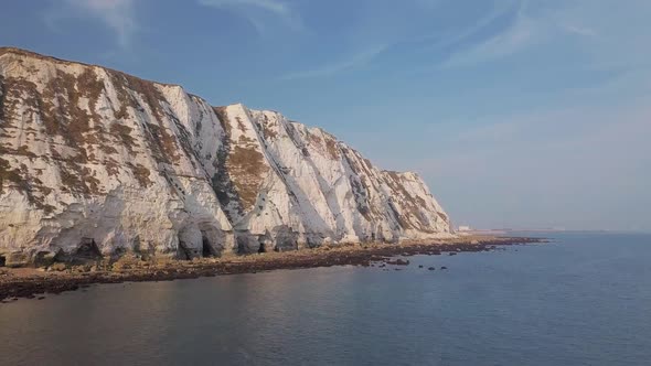 Drone flies low towards White Cliffs of Dover, slowly rising. Beautiful turquoise sea in the foregro