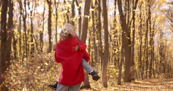 Young Blond Mother with Daughter Walk in the Autumn Forest