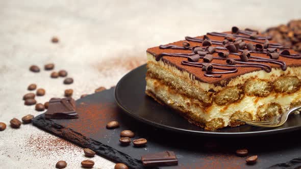 Portion of Traditional Italian Tiramisu dessert on grey concrete background