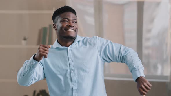 Happy Adult Smiling African Man Dancing Sit at Office Desk Has Break in Work American Carefree