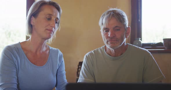 Senior caucasian couple using laptop and sitting at table