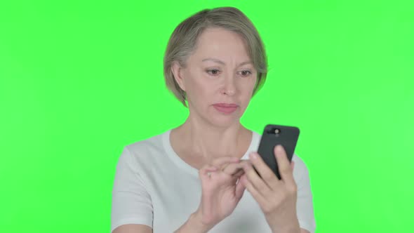 Old Woman Browsing Smartphone on Green Background