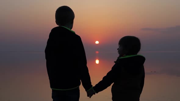 Children Looking at Sunset Under Calm Water