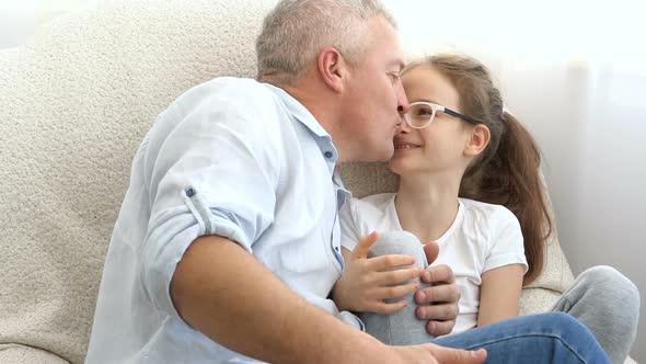 Cute Daughter is Kissing Her Greyhaired Father with Love at Home Father's Day Concept