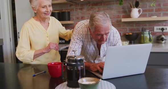 Senior Caucasian couple happily working together on a laptop at home