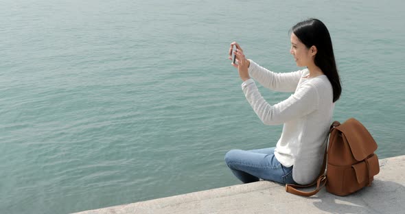 Woman taking the photo on cellphone with seascape