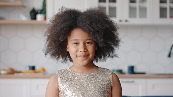 Indoors Portrait of Little Curly African American Girl Smiling to Camera Posing at Home