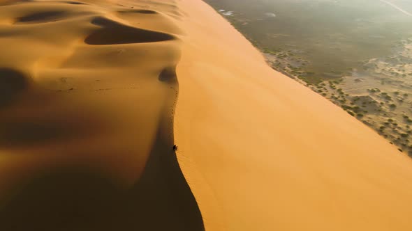 Aerial view of a man sitting on the edge of dunes, U.A.E.