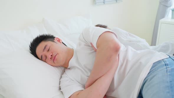 Asian young couple lying down on bed with painful after fight argument.